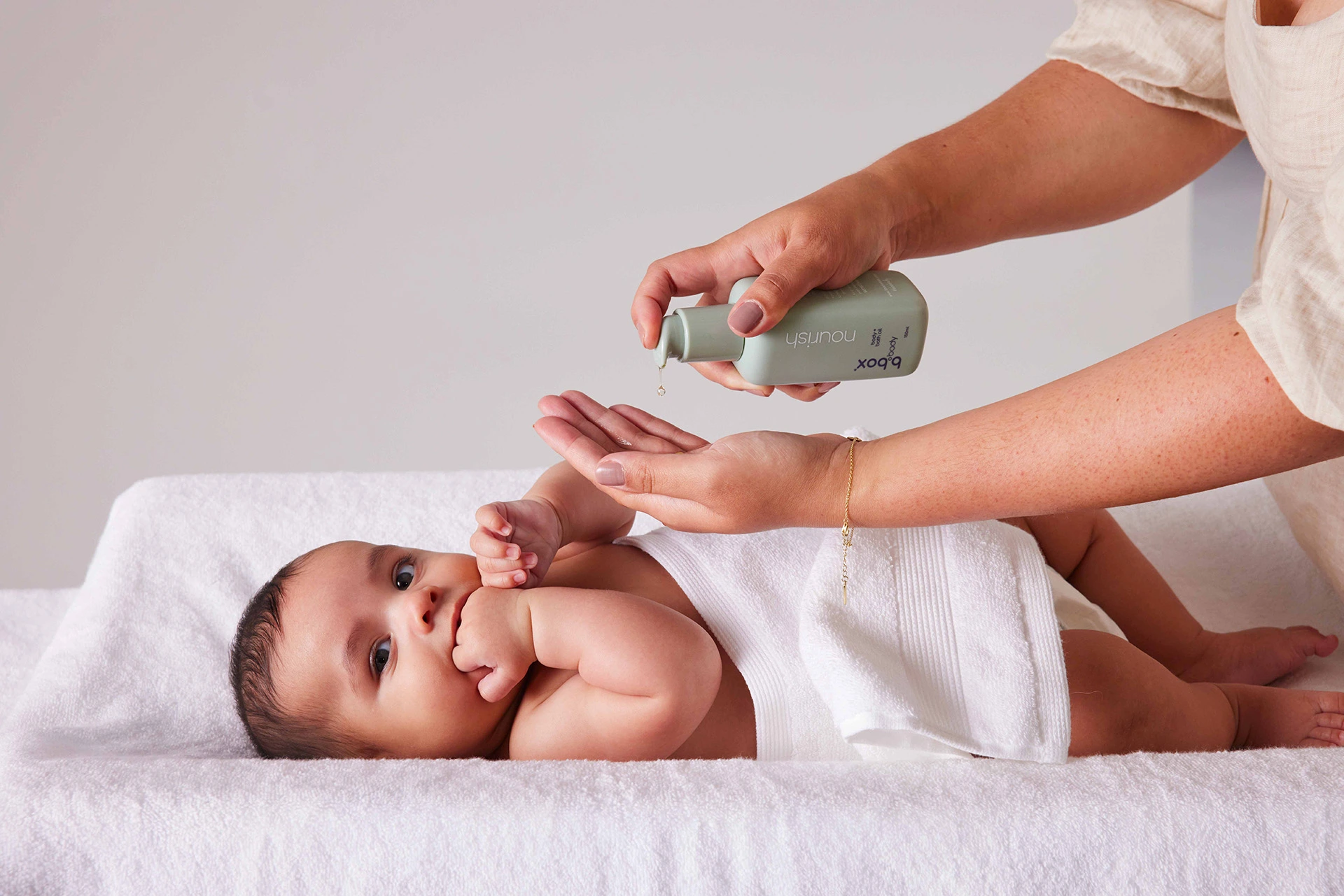 A mother applying nourish, body and bath oil, to her baby